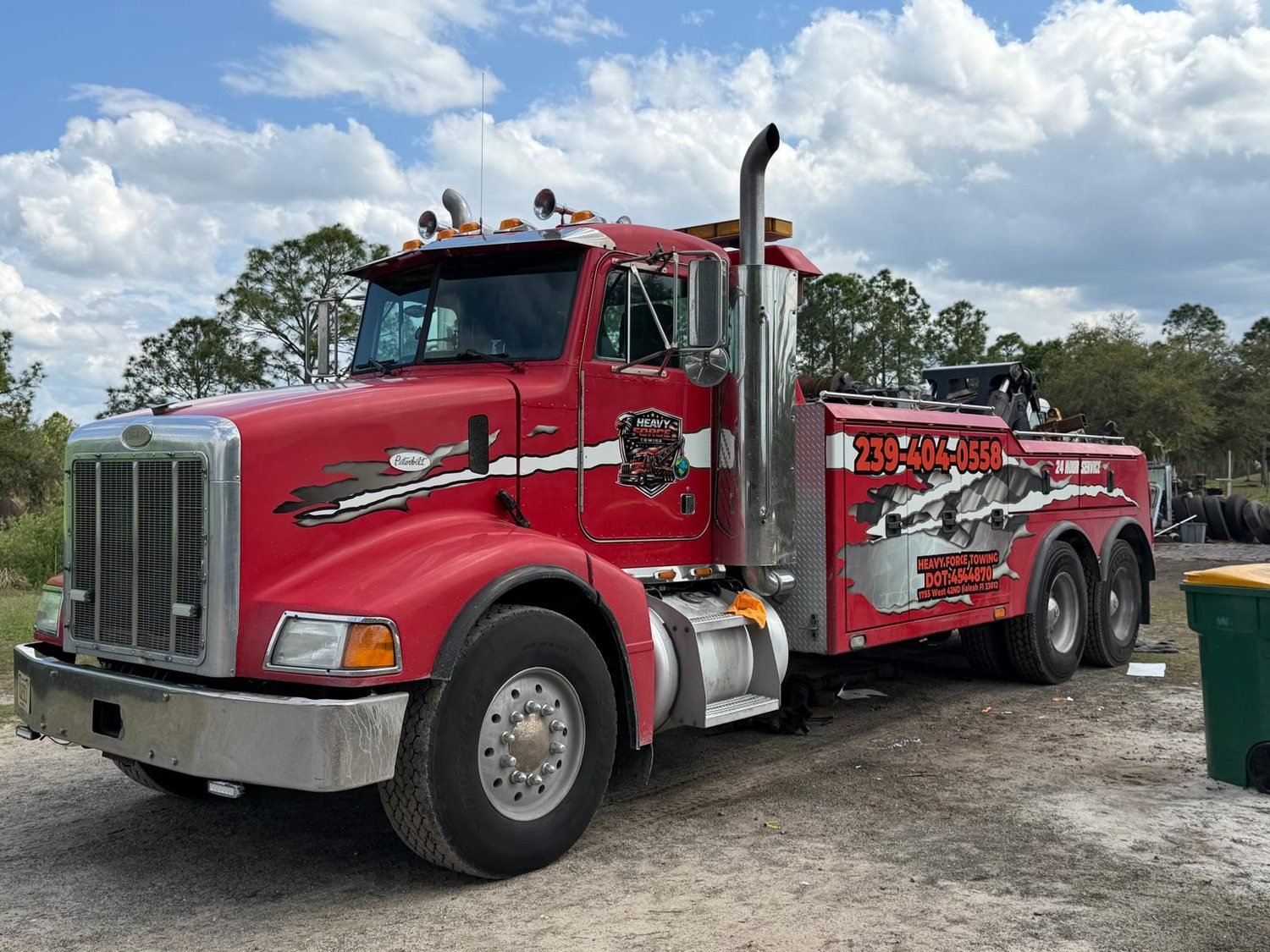 The red Peterbilt heavy wrecker in daylight, door lettered with the Heavy Force logo, 239-404-0558, DOT 4544870 and 24 hour service